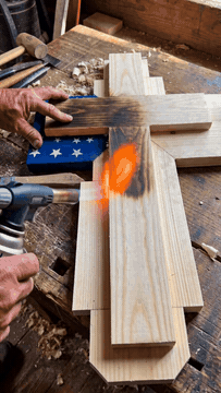 Torch-burning the wooden cross by hand